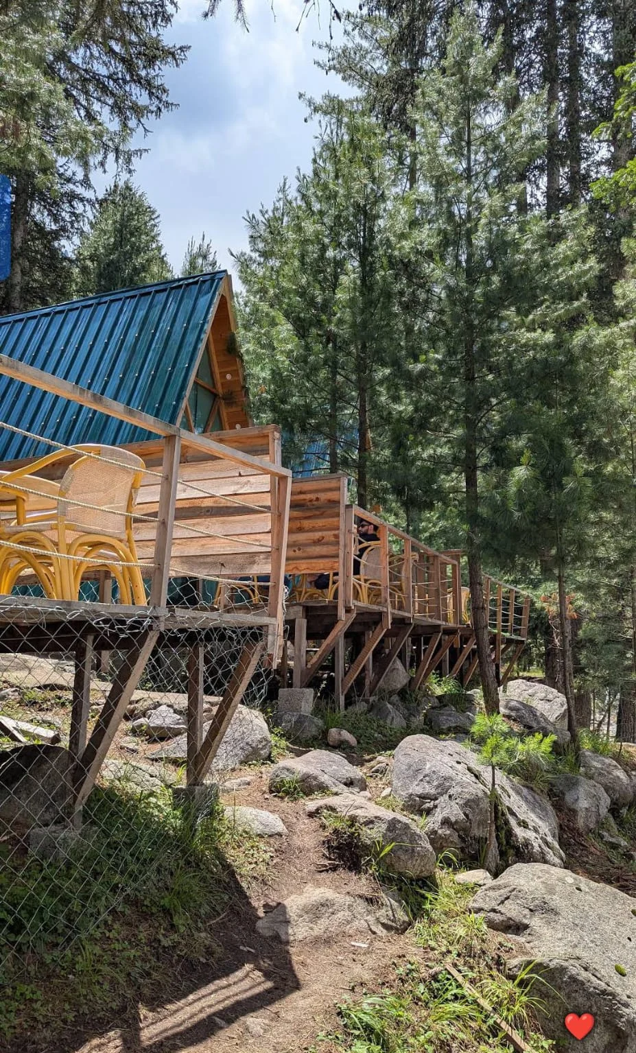 The blue-roofed A-frame and timber terrace among trees