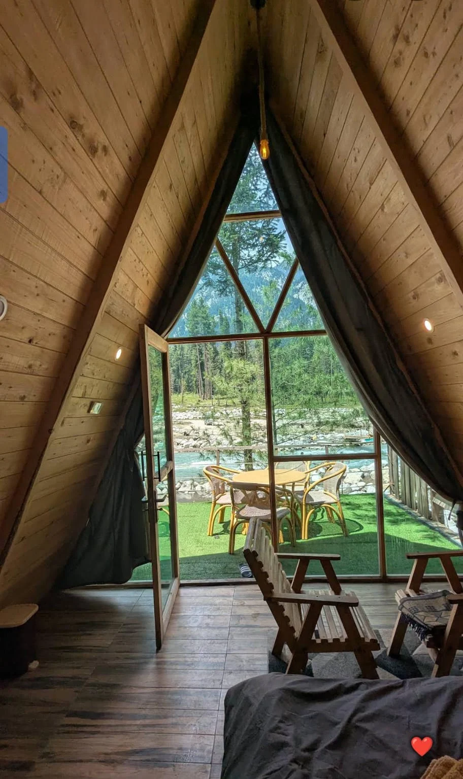Inside the A-frame, looking through geometric triangular windows toward the forest